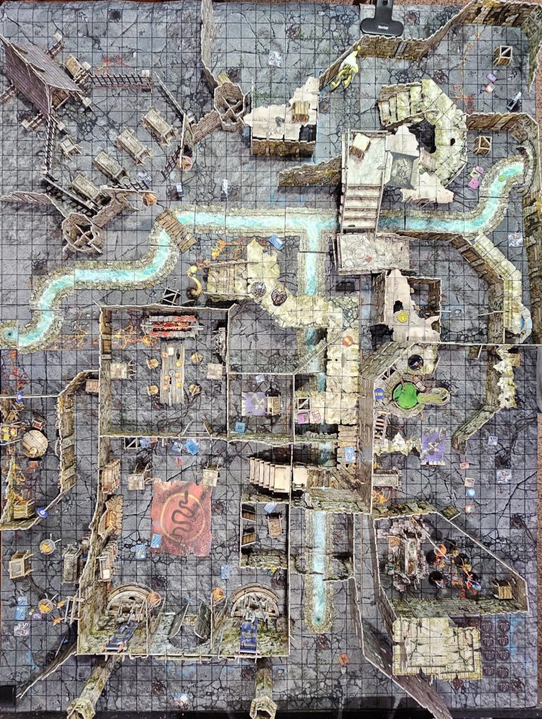 Top-down view of Nathan’s custom 4x3 gaming table filled with highly detailed Maladum and Battlesystems terrain, including buildings, rivers, ruins, and painted miniatures. An immersive fantasy battlefield setup before the house fire.