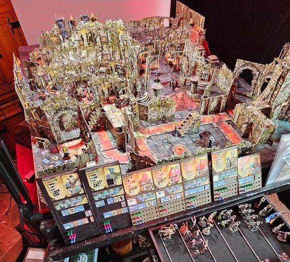 Large 4x3 custom gaming table filled with highly detailed Maladum and Battlesystems terrain, painted miniatures, cards, and gaming accessories. A massive, immersive fantasy battlefield setup.