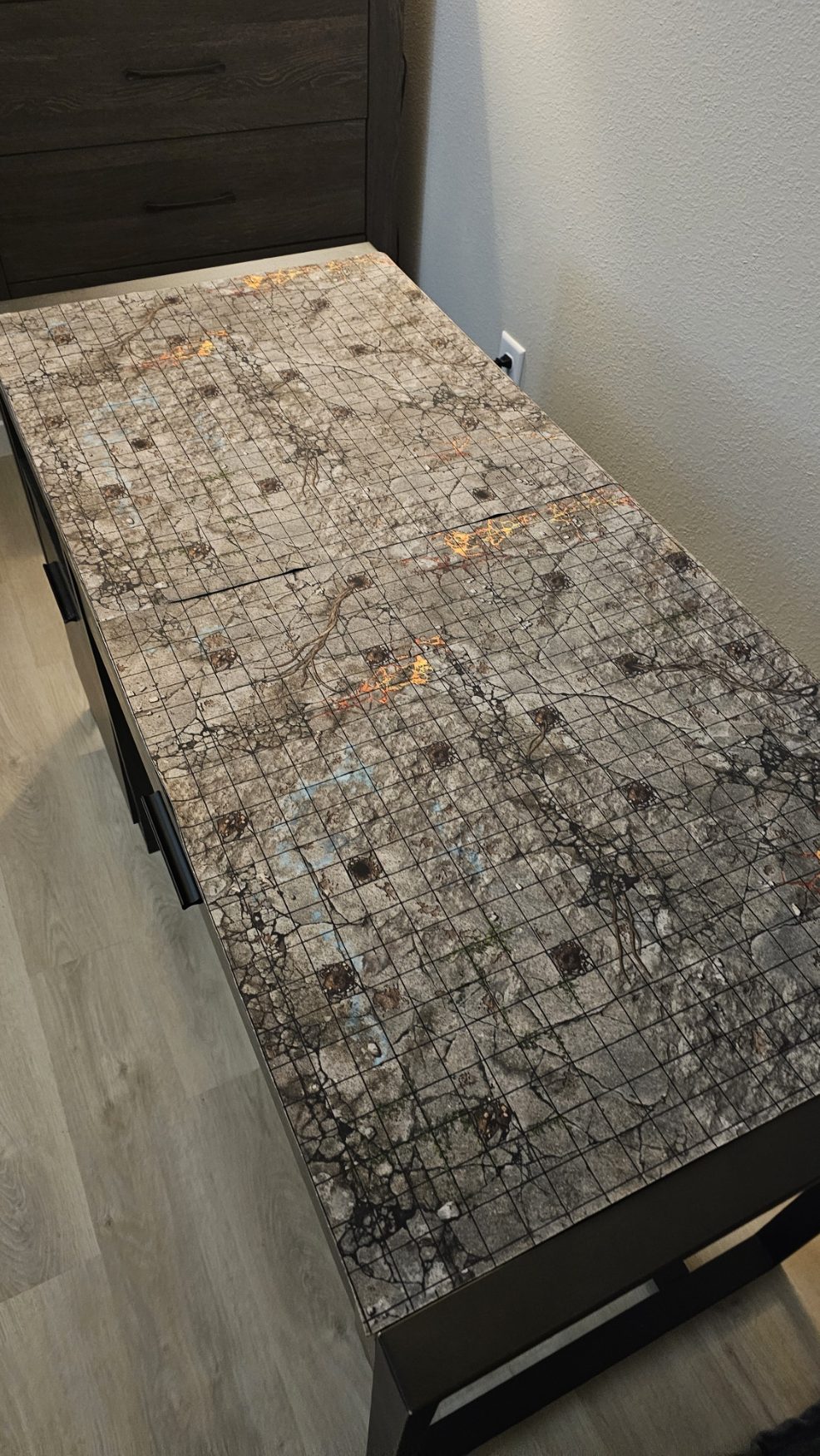 Clean 2x4 gaming table setup with a detailed camouflage battle mat in a modern apartment, marking the beginning of a new chapter after the house fire.
