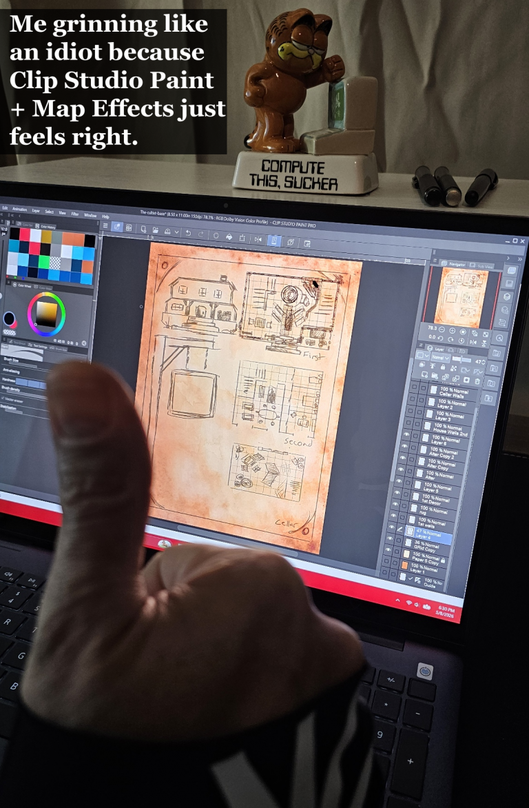 Hand holding up a thumbs-up in front of a Dell 2-in-1 laptop running Clip Studio Paint. The screen shows a detailed fantasy map of a cultist base. A Garfield 'Compute This, Sucker' figurine sits on top of the laptop in a cozy setup.